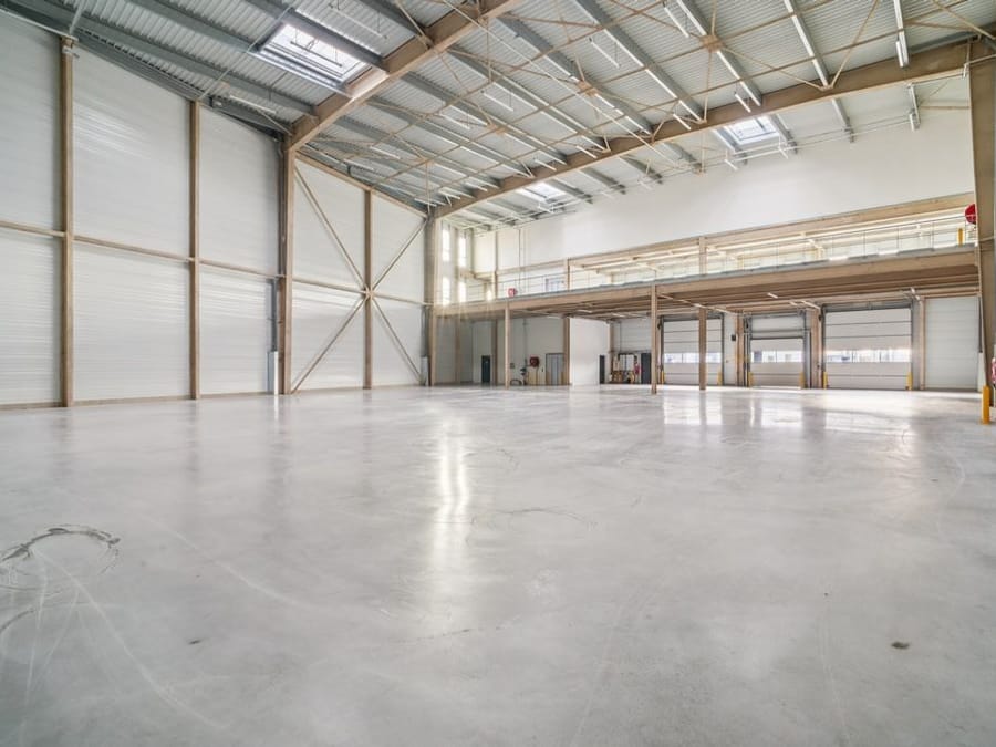 Entrepôt logistique vide, sol béton lissé après passage de l'autolaveuse